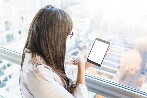 Rear view of businesswoman pointing finger on digital tablet with blank white screen