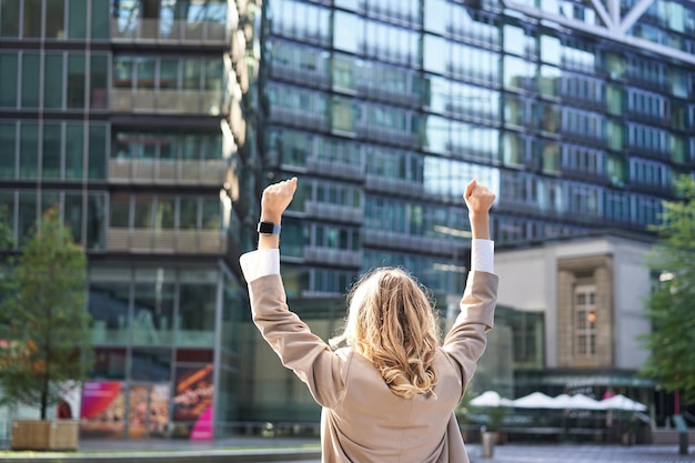 Foto gratuita vista posteriore dell'avvocato donna aziendale che celebra alzando le mani e trionfando per raggiungere l'obiettivo o il successo