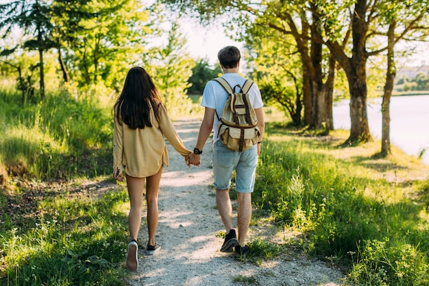 Rear view of couple holding hands walking on footpath