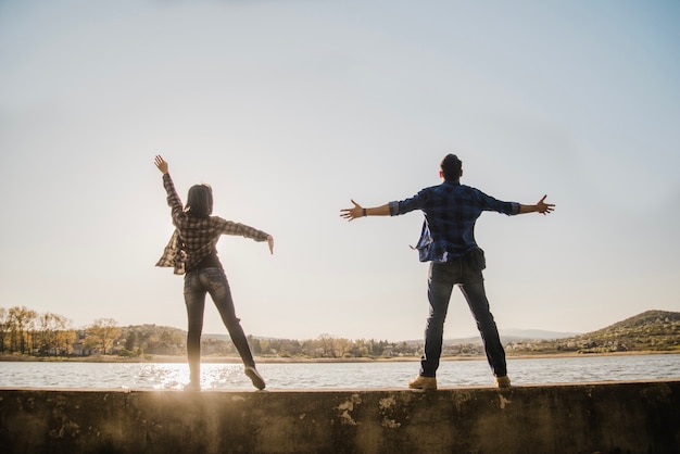 Free photo rear view of couple with open arms looking up at the sky