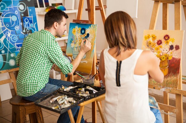 미술 학교에서 공부하는 동안 자신의 그림을 작업하는 몇 명의 젊은 성인의 뒷모습
