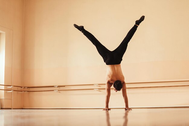Free photo rear view of a dancer exercising in a studio and doing a handstand copy space