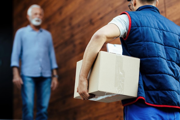 Rear view of delivery man carrying a package to his customer