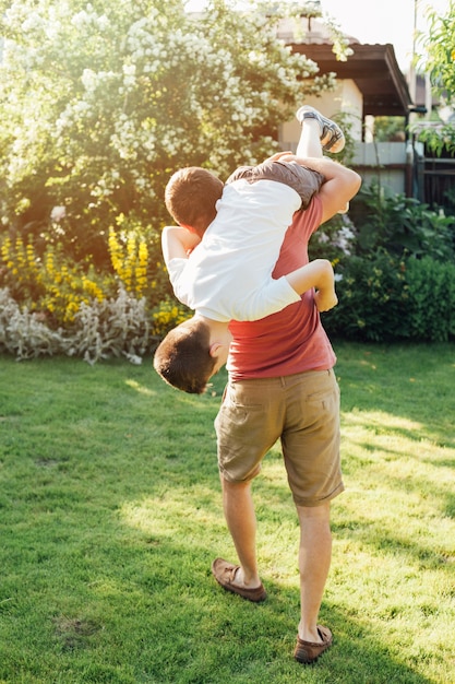 Rear view of father carrying his son in park