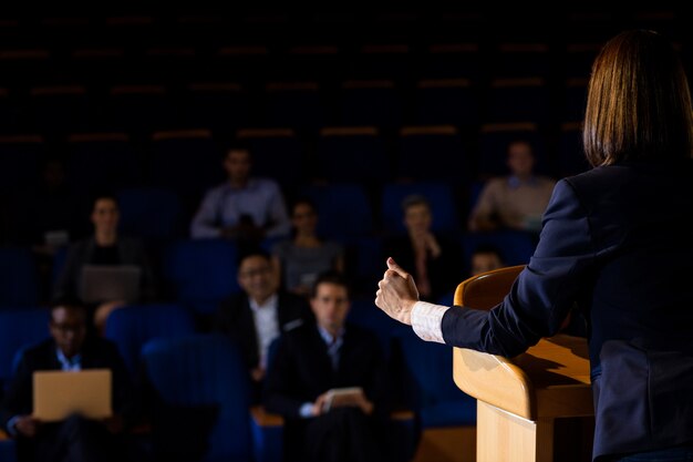 Rear view of female business executive giving a speech