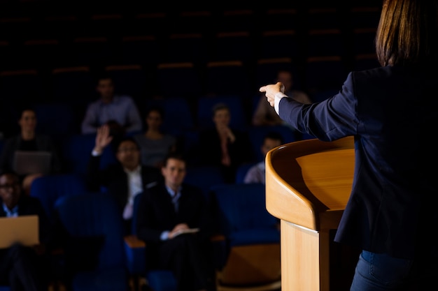 Free photo rear view of female business executive giving a speech