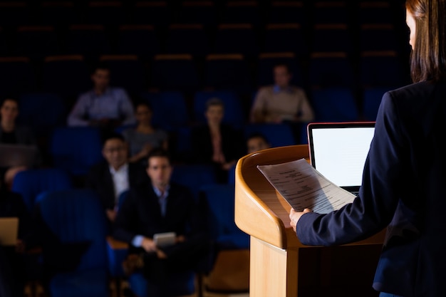 Rear view of female business executive giving a speech