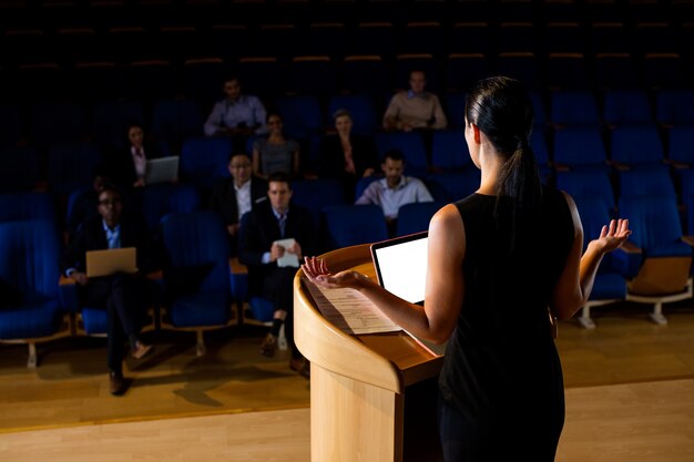 Rear view of female business executive giving a speech