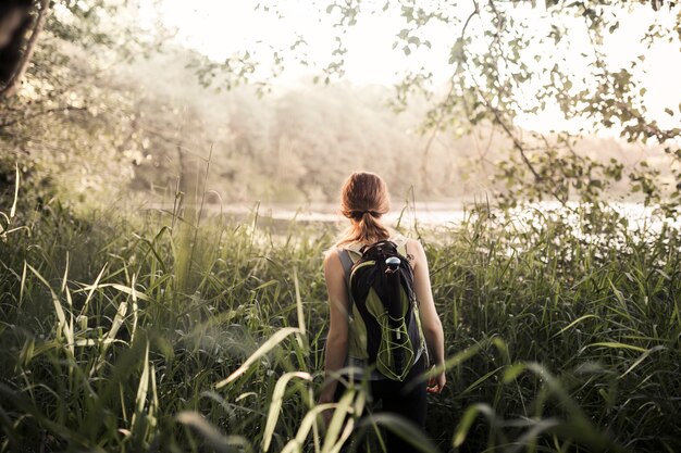 Rear view of female hiker walking in the green grass