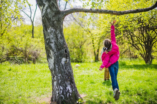 Free photo rear view of girl jumping under a branch