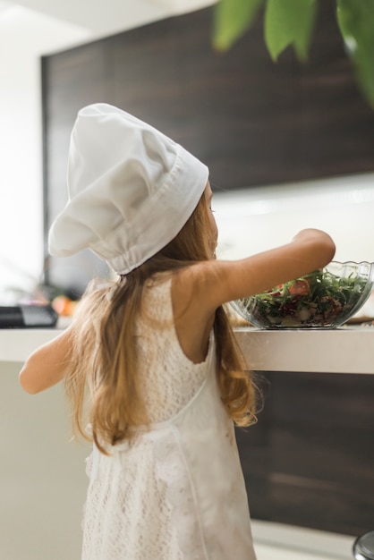 台所でサラダを準備する女の子の背面図