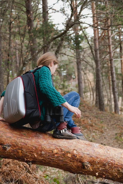 Rear view of girl sitting on a log