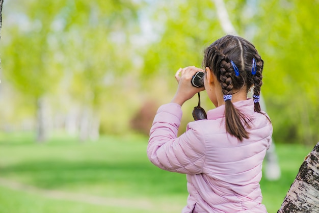 Vista posteriore della ragazza con il binocolo nel parco