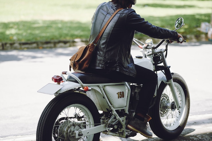 無料Photo 道路に沿ってバイクに乗って男性バイカーの背面図