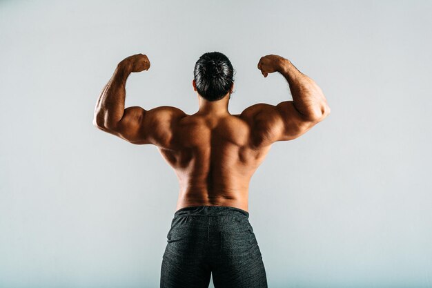 Rear view of a male bodybuilder showing muscles on his arms