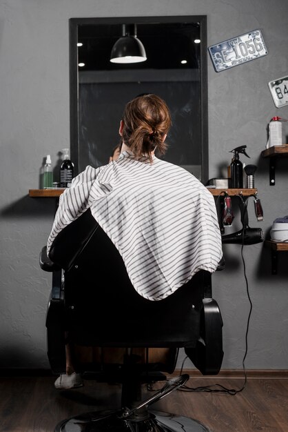 Вид сзади мужчины-клиента, сидящего на кресле в парикмахерской