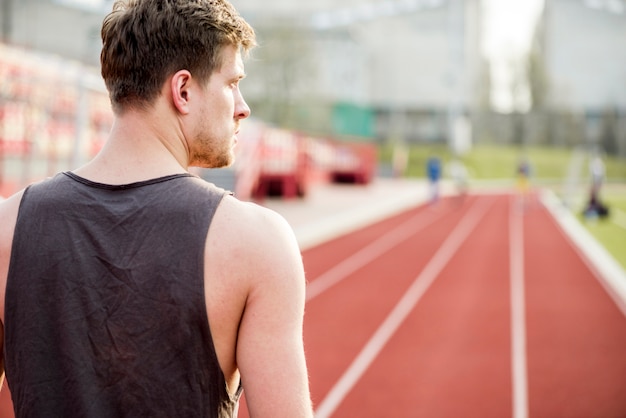 Rear view of a male runner standing on race track looking away