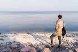 Free photo rear view of a male traveler looking at calm seascape