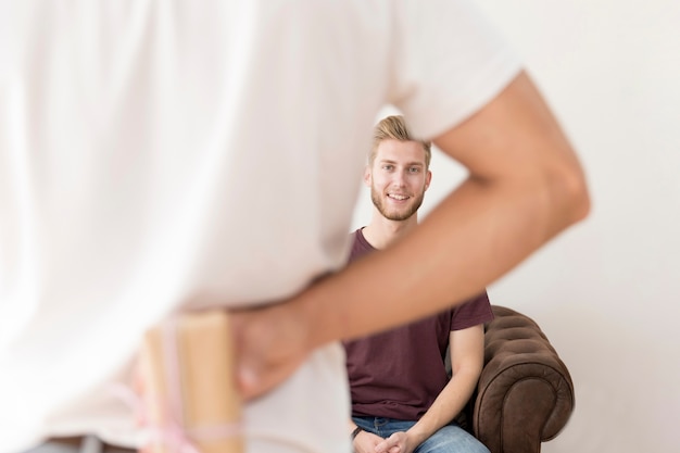 Rear view of man hiding gift box from his friend