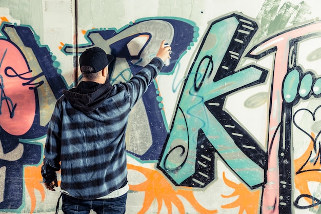 Rear view of a man making graffiti on wall