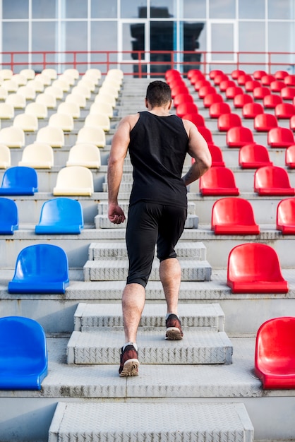 Rear view of a man running up stairs on the bleacher