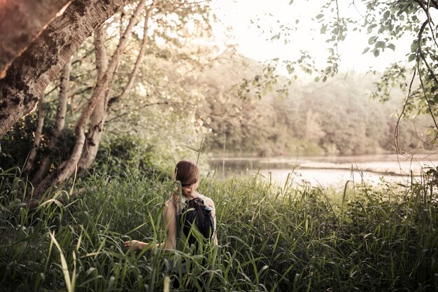 Вид сзади человека, стоящего в траве, глядя на озеро