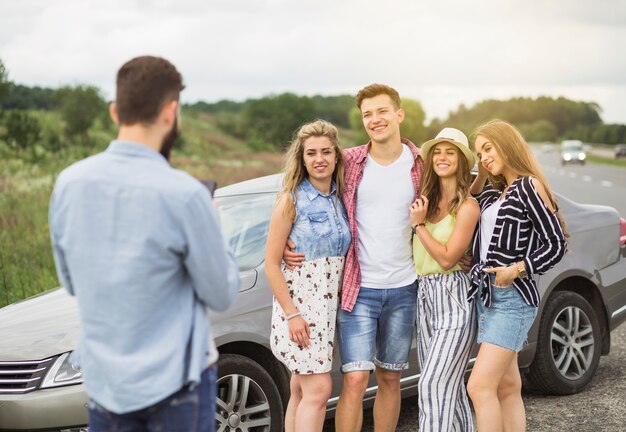 Retrovisione dell'uomo che prende immagine dei suoi amici che stanno vicino alla nuova automobile