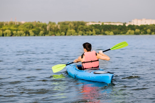 Rear view of man using paddle for kayaking