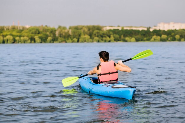 Rear view of man using paddle for kayaking