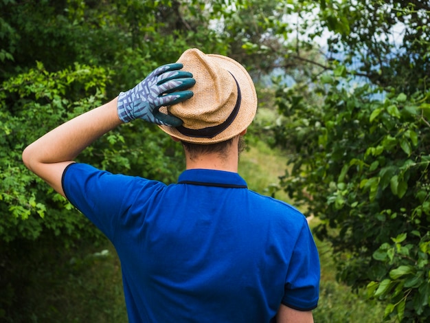 Free photo rear view of man wearing glove touching his hat on head