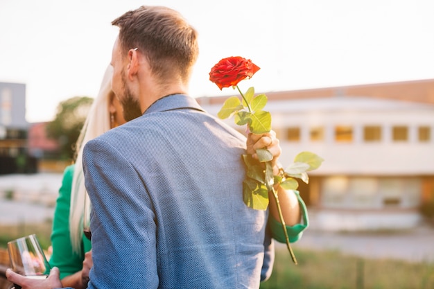 Foto gratuita vista posteriore dell'uomo con la sua ragazza che tiene bella rosa rossa in mano