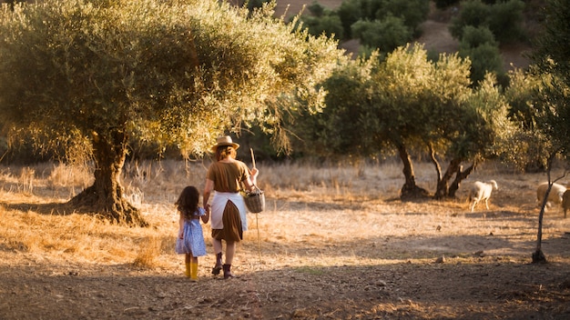 Rear view of mother and her daughter walking in the field