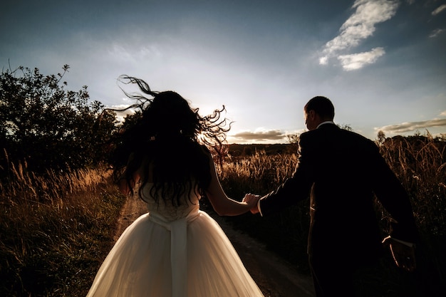 Rear view of newlyweds walking at sunset