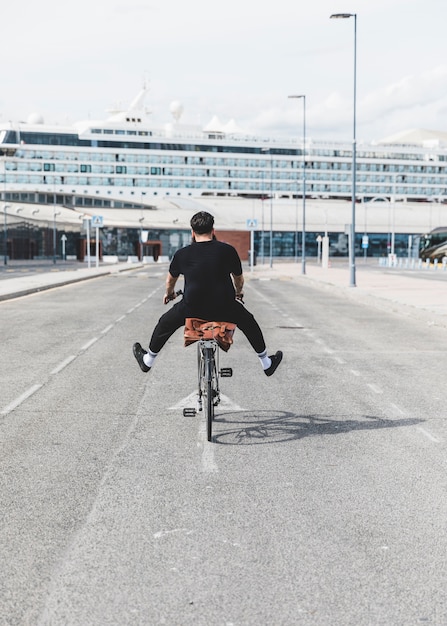 Бесплатное фото Вид сзади человека, едущего на велосипеде с его протянутой ногой о дороге