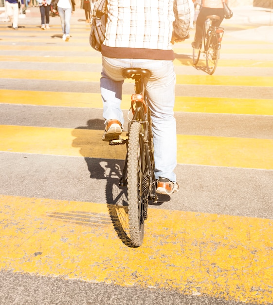 道路上に印刷された黄色の縞模様の自転車に乗って人の背面図