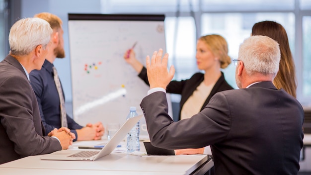 Free photo rear view of senior businessman asking questions during presentation