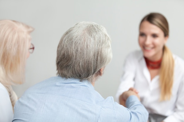 Retrovisione al consulente senior di handshaking delle coppie o al lavoratore medico