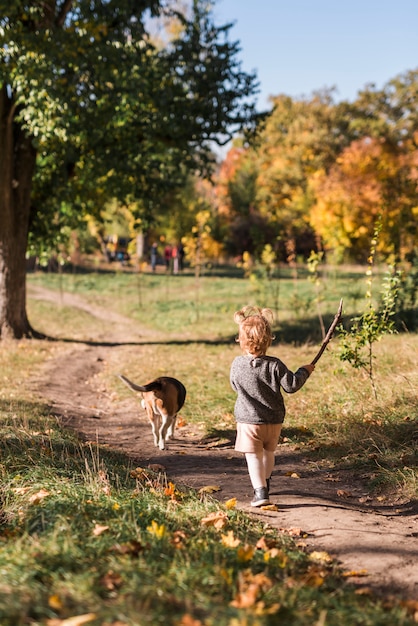 숲의 흔적에 그녀의 애완 동물 강아지와 함께 산책 작은 소녀의 후면보기