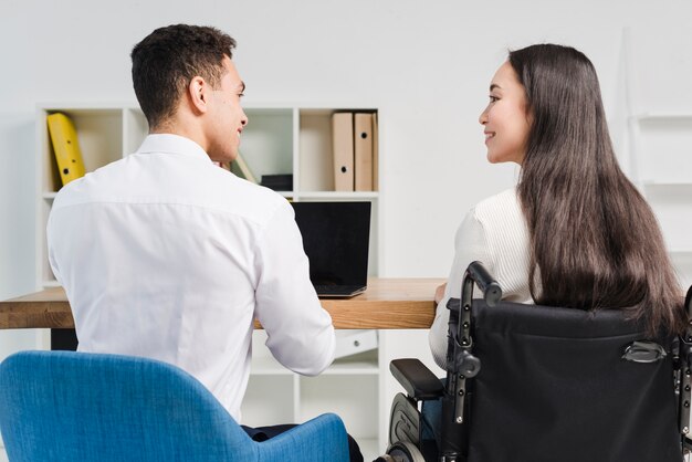 Rear view of a smiling young business people looking at each other at workplace