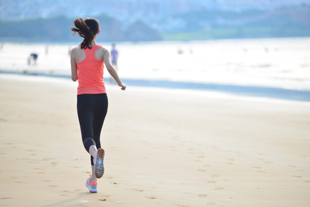 Rear view of sportswoman running on the seashore