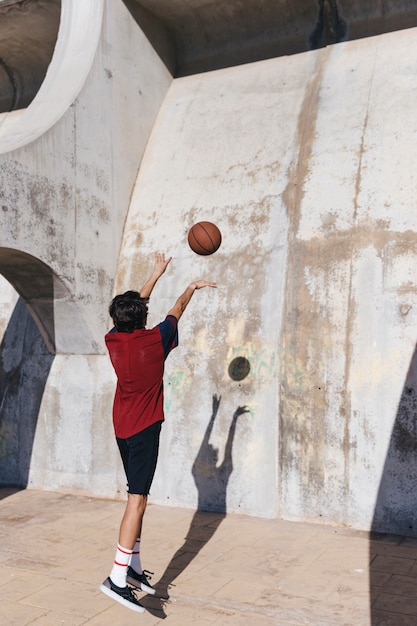 Rear view of a teenage boy practicing basketball