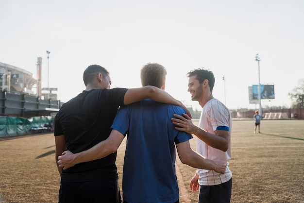 Вид сзади трех мужских друзей на стадионе