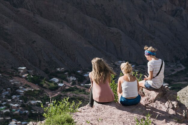 Rear view of three women sitting on top of the mountain