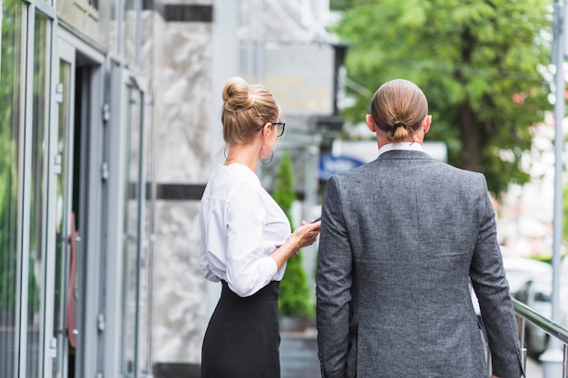 Rear view of two businesspeople standing outside office