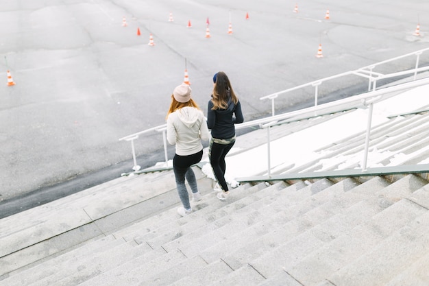 Rear view of two female jogging on the staircase in the winter