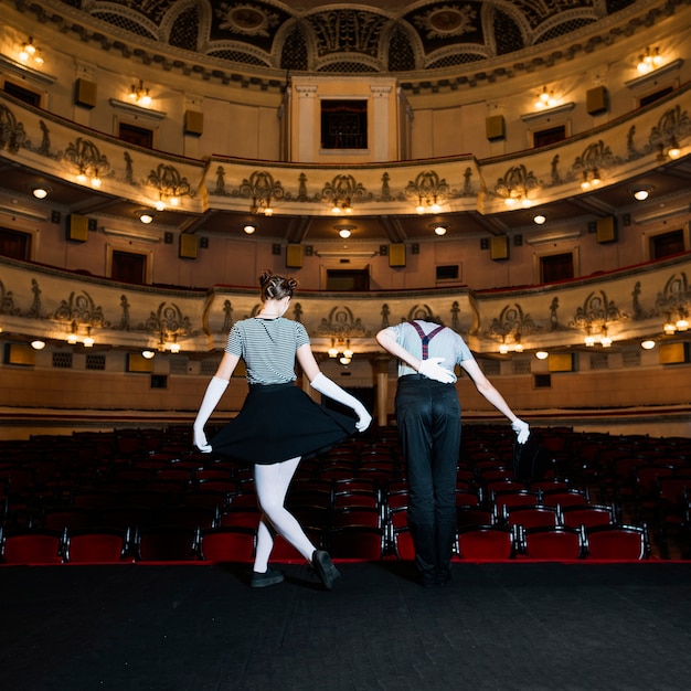 Free photo rear view of two performer bowing on stage