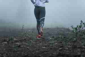 Foto gratuita retrovisione della donna atletica irriconoscibile che corre nella nebbia