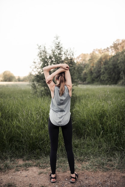 Rear view of woman standing in green field exercising