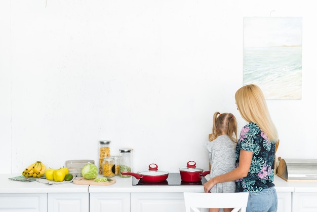 Rear view of a woman with her daughter in kitchen