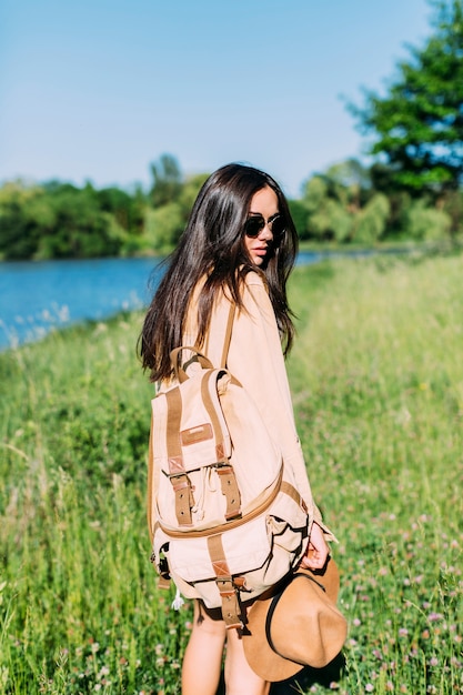rear view of woman with holding backpack and brown hat